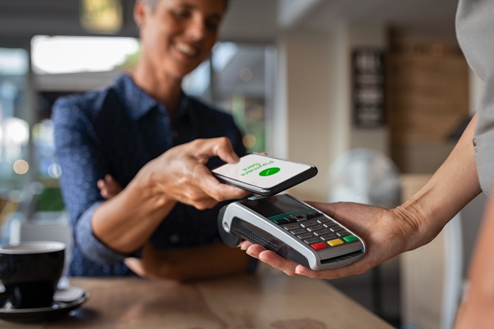 Customer paying with a phone at a cafe card terminal